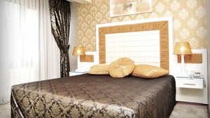 A hotel room with a large bed, two bedside tables with lamps, a headboard with a decorative panel, and a framed picture on the wall. - Pen Hotel (Istanbul)