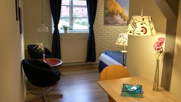 A room with a bed, a desk, a chair, a lamp, and a window with curtains.