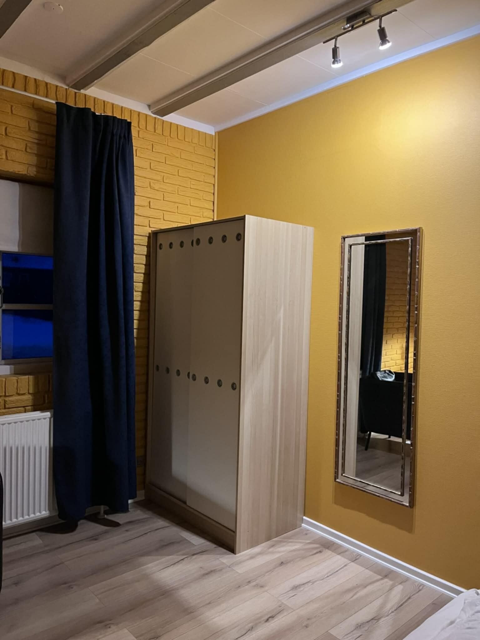 Una stanza con un armadio, uno specchio e un termosifone.