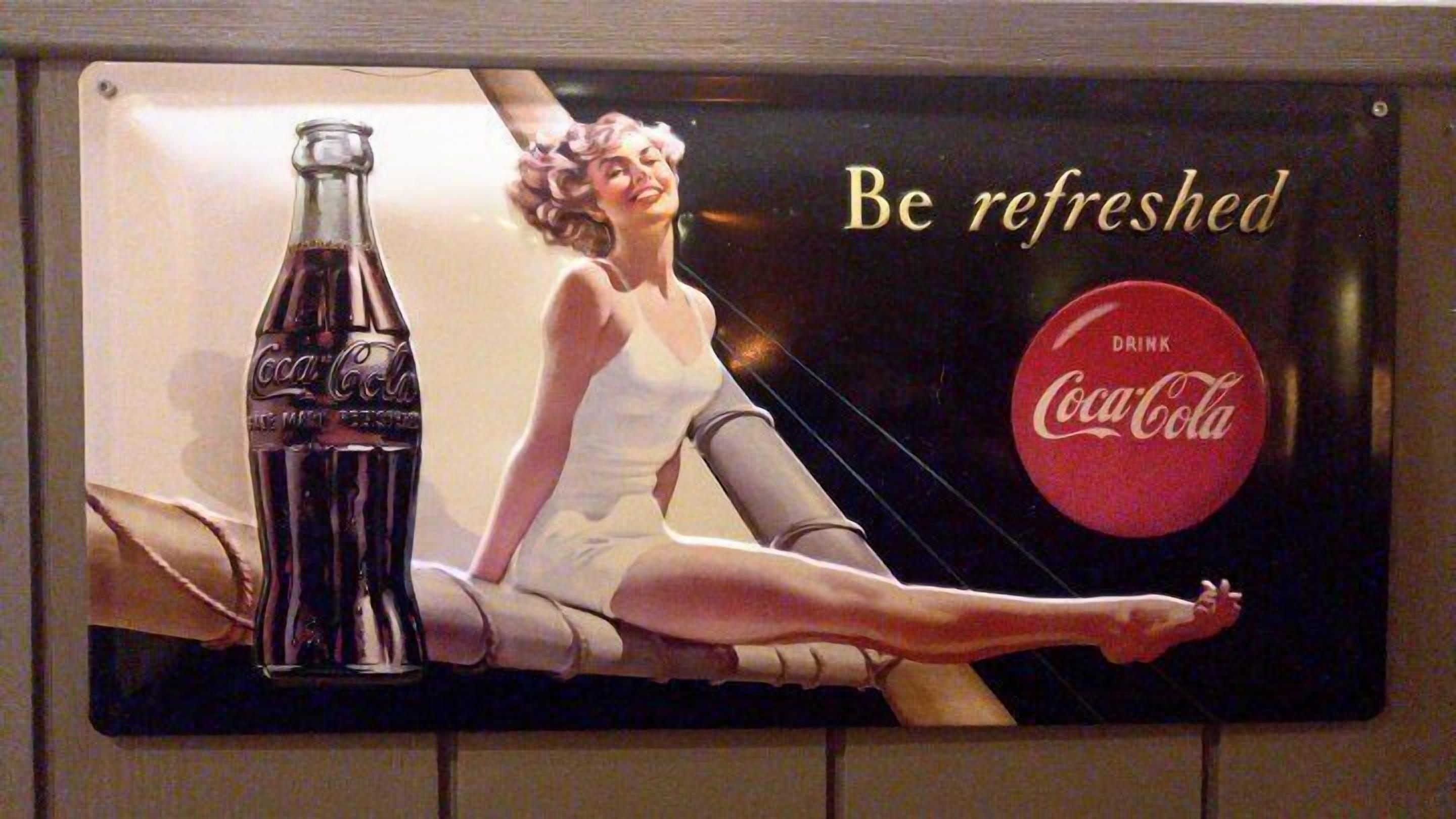 A vintage Coca-Cola advertisement featuring a woman in a white dress and a bottle of Coca-Cola.