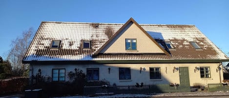 Een herenhuis met twee verdiepingen, een puntgevel, een groene deur en een klein portaal.