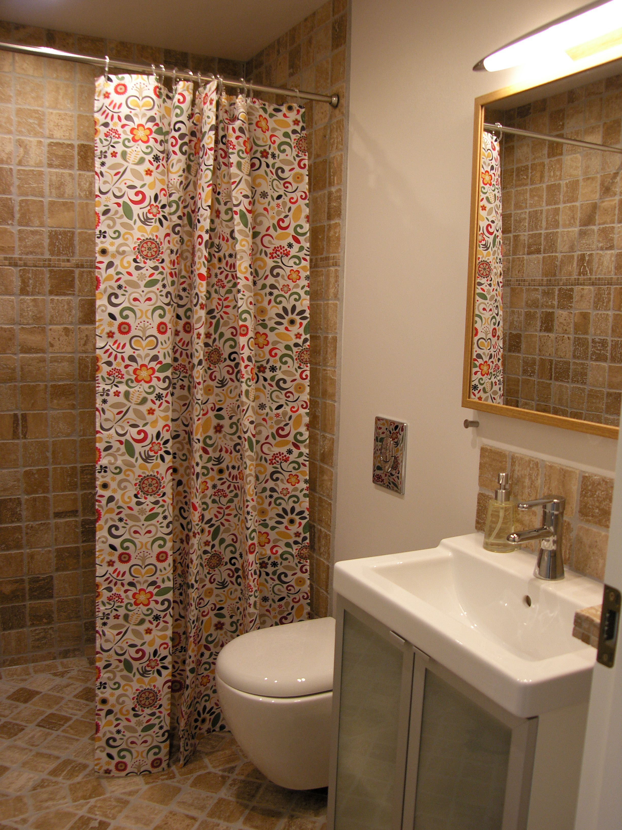 A bathroom with a shower curtain, toilet, sink, and mirror.