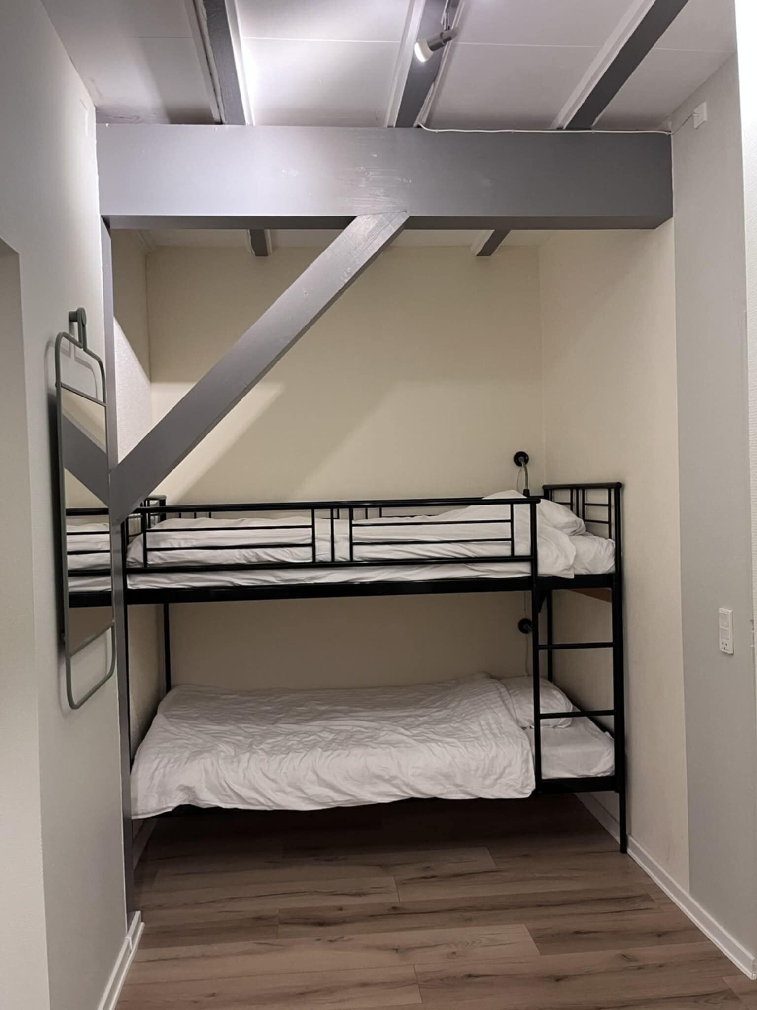 Habitación con literas, techo inclinado y suelo de madera.