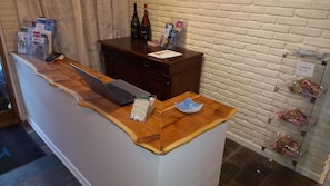 A reception desk with a laptop, brochures, and a wine bottle. - Klintholm Bed & Breakfast (Borre)