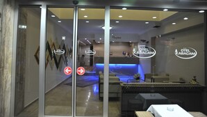 Vestíbulo de hotel con mostrador de recepción, zona de estar y una pared de vidrio con indicaciones.