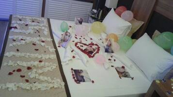 A bed with rose petals, balloons, and a heart-shaped decoration.