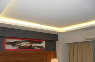 Habitación de hotel con un diseño moderno en el techo, un cuadro abstracto grande y un equipo de aire acondicionado.