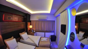 A hotel room with two beds, a TV, an air conditioner, and a window with curtains.