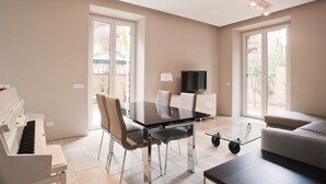 A modern living room with a piano, a glass dining table, and a sofa. - Rent In Rome - Vatican Deluxe (Rome)