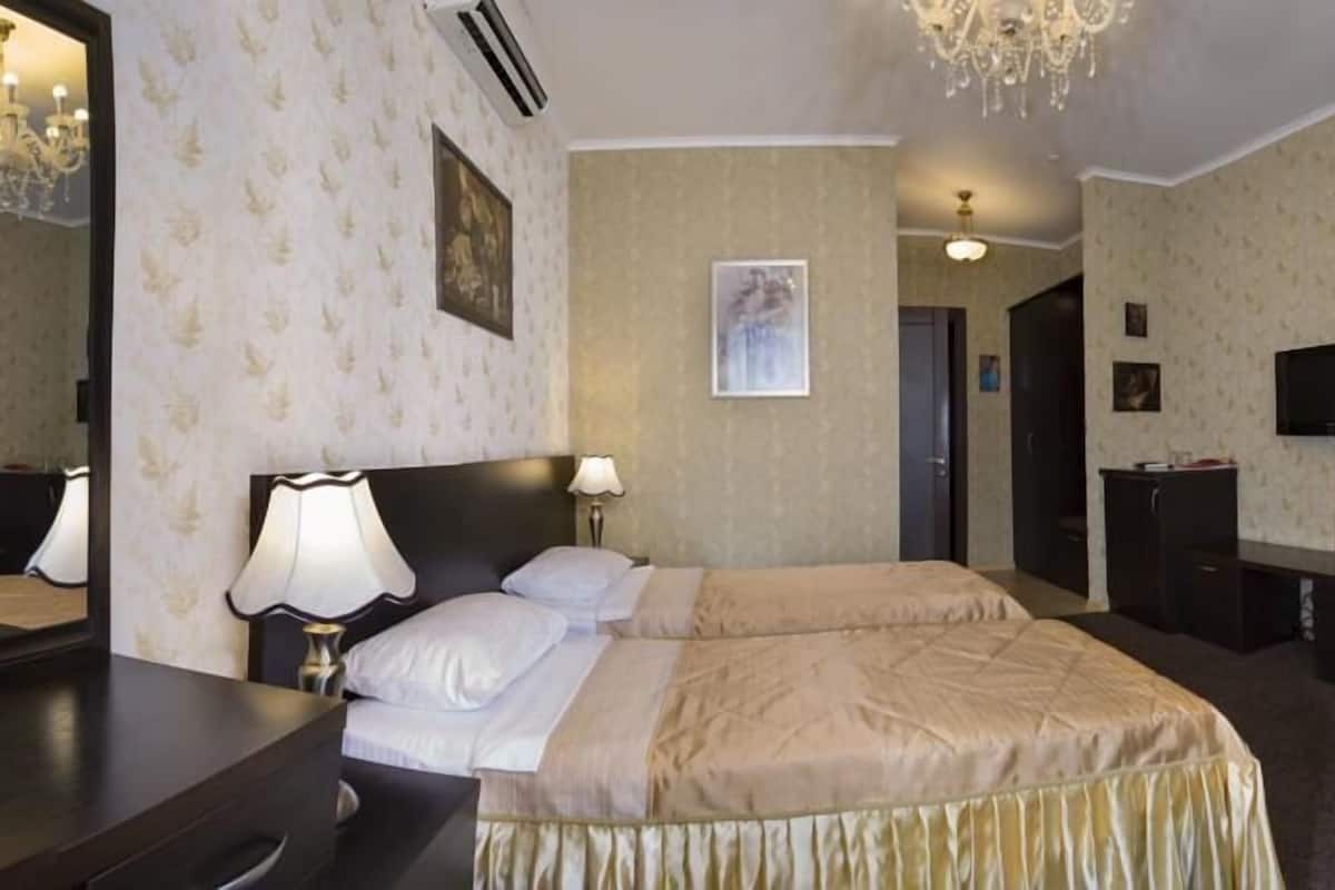 A hotel room with a double bed, bedside lamps, a dresser, a television, and a mirror.