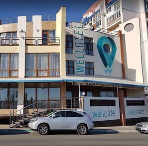 Ein Gebäude mit einem auffälligen 'WELLLOTE'-Schild und 'wellcafe'-Branding, das ein modernes Design mit Balkonen und großen Fenstern aufweist.