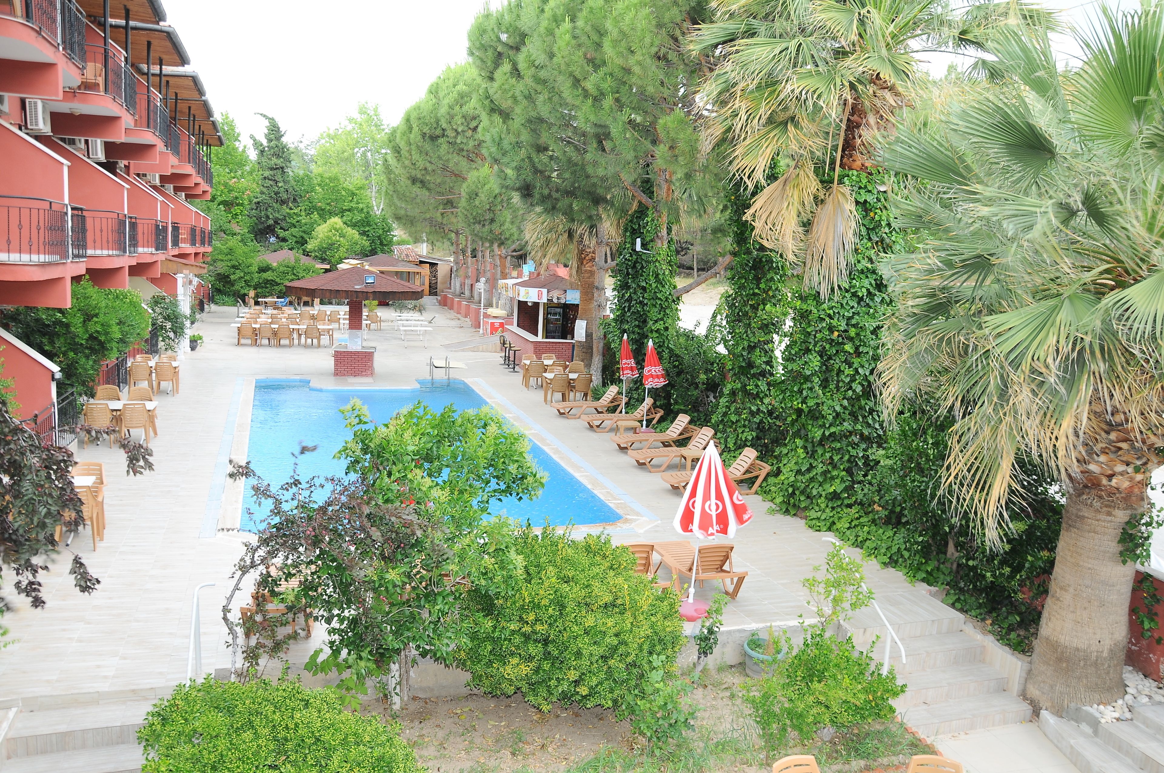 A pool area with lounge chairs, a small bar, and a staircase leading to a building with balconies.