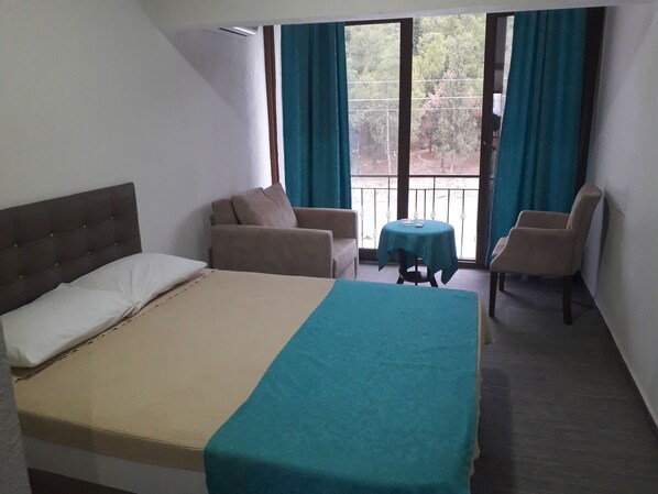 A hotel room with a bed, two armchairs, a small table, and a balcony with a view. - OSKAR HOTEL (Denizli)