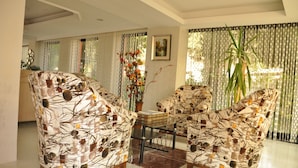 Una sala de estar con muebles estampados, una mesa de centro y una planta grande.
