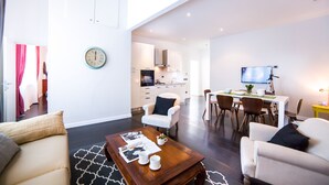 A modern living room with a sofa, coffee table, and dining area. - Rent In Rome - Flo's Apartment (Rome)