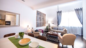 A modern living room with a dining area, a sofa set, and a kitchen visible through an open door. - Rent In Rome - Flo's Apartment (Rome)
