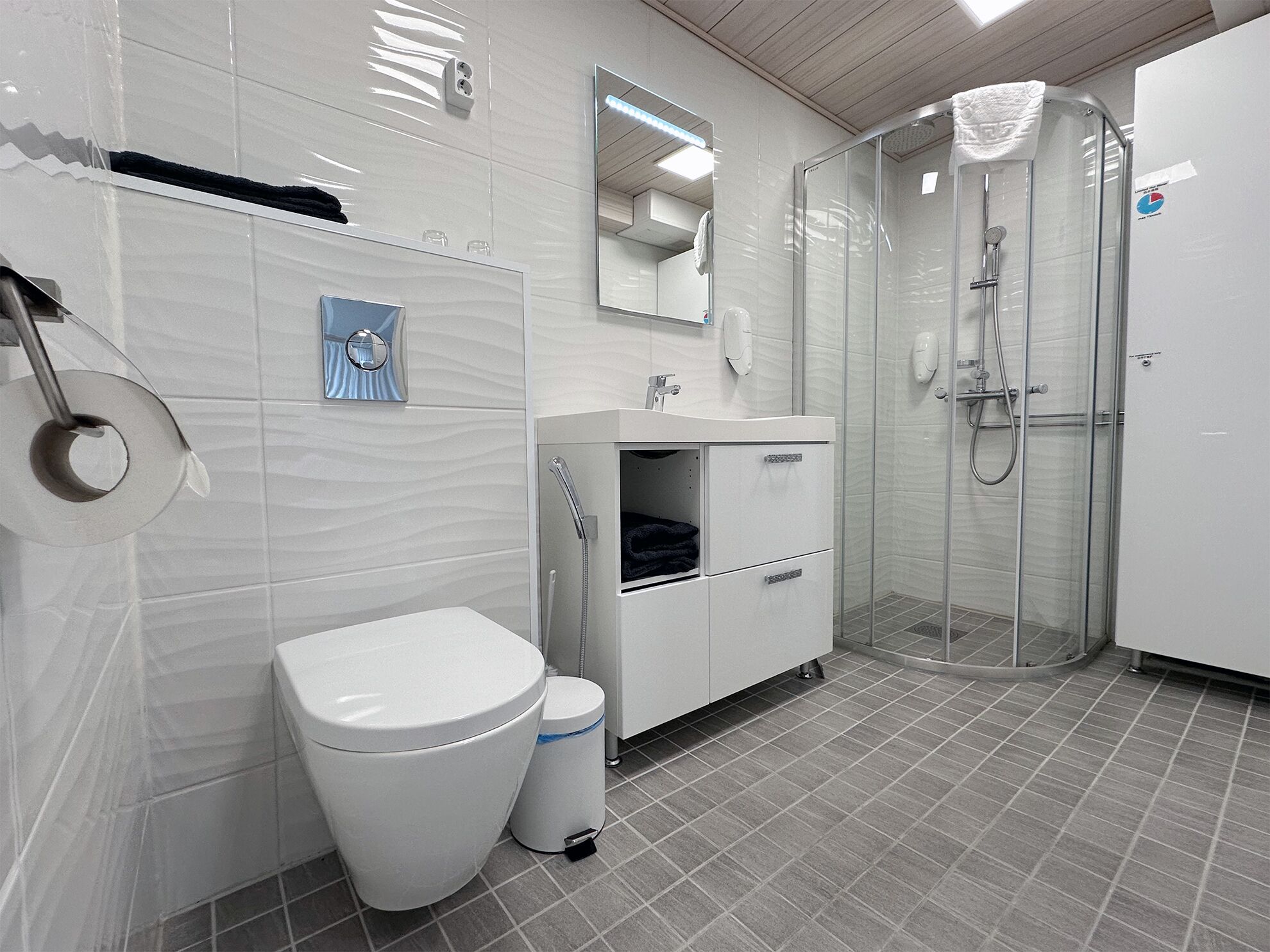 A modern bathroom with a toilet, sink, and shower.