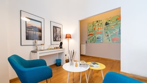 A modern living room with blue chairs, a white desk, and a map on the wall. - Duomo Hermes Relais (Naples)