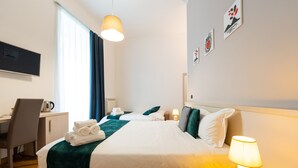 A hotel room with a bed, a desk, a chair, a lamp, and artwork on the wall. - Duomo Hermes Relais (Naples)