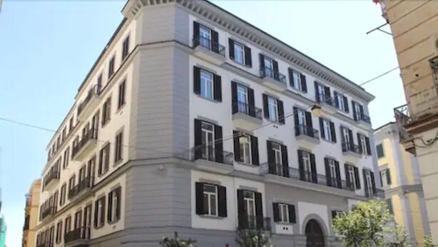 A multi-story building with a classical architectural style, featuring a symmetrical facade, multiple windows, and balconies. - Duomo Hermes Relais (Naples)