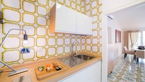 A modern kitchen with a hexagonal tile backsplash, a wooden countertop, and a dining area with a table and chairs. - Rent In Rome - Vittoria Terrace (Rome)