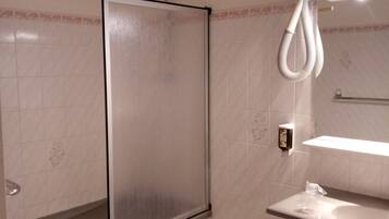 Un baño con ducha, un lavamanos, un bidé y un espejo.