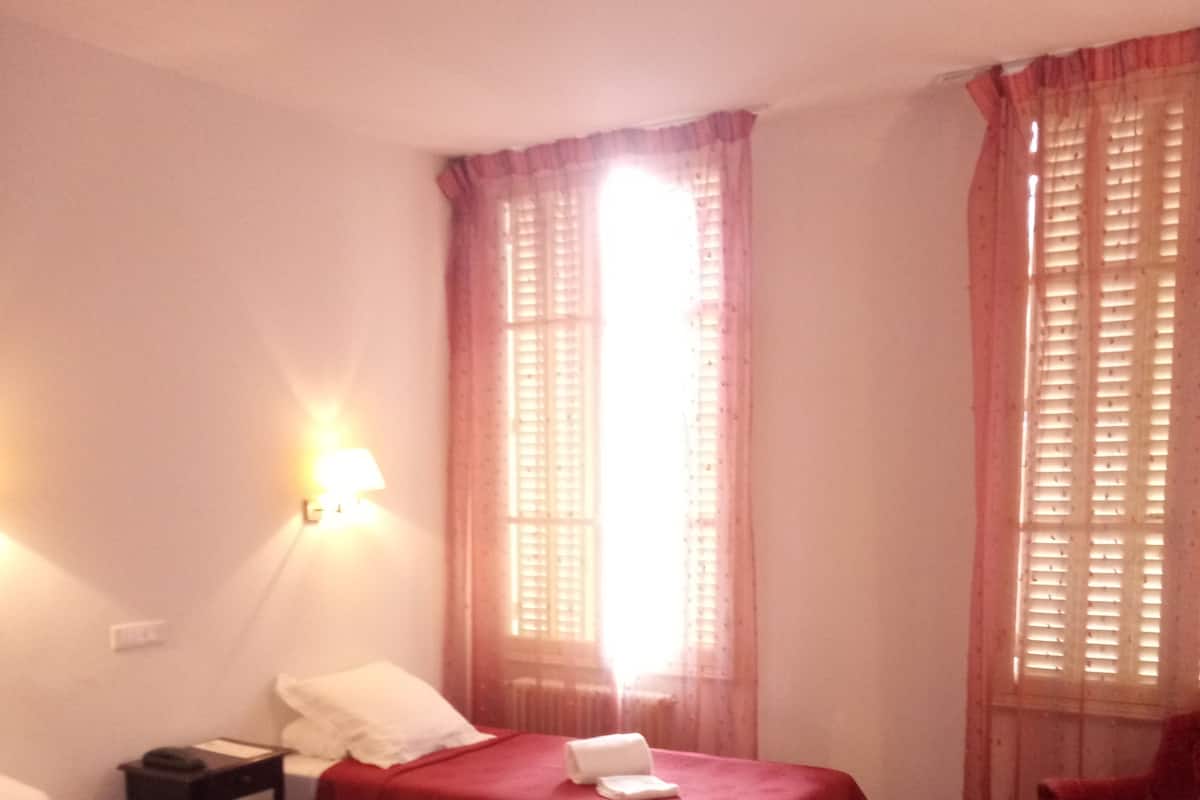 Een hotelkamer met twee bedden, een bureau en een stoel.
