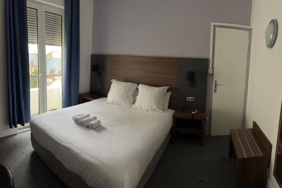 Een hotelkamer met een groot bed, nachtkastjes, een spiegel en uitzicht.