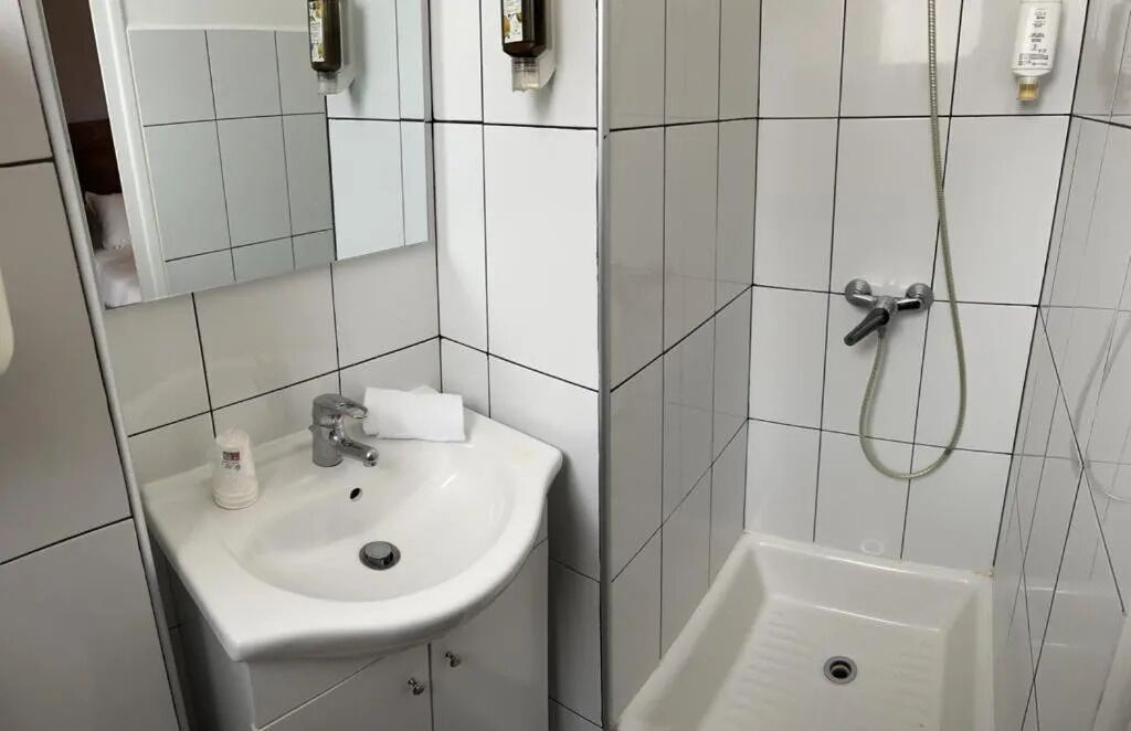 A bathroom with a white sink, mirror, and shower.