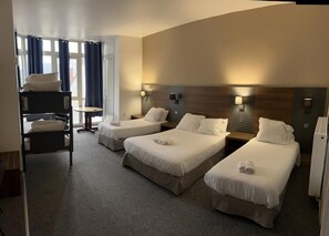 A hotel room with three single beds, a small desk, and a chair. - Hôtel Moderne (Vichy)