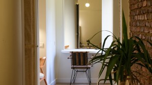 A bathroom with a white sink, a mirror, and a chair. There is a plant in the foreground. - The Wilson Galata Hotel (Istanbul)
