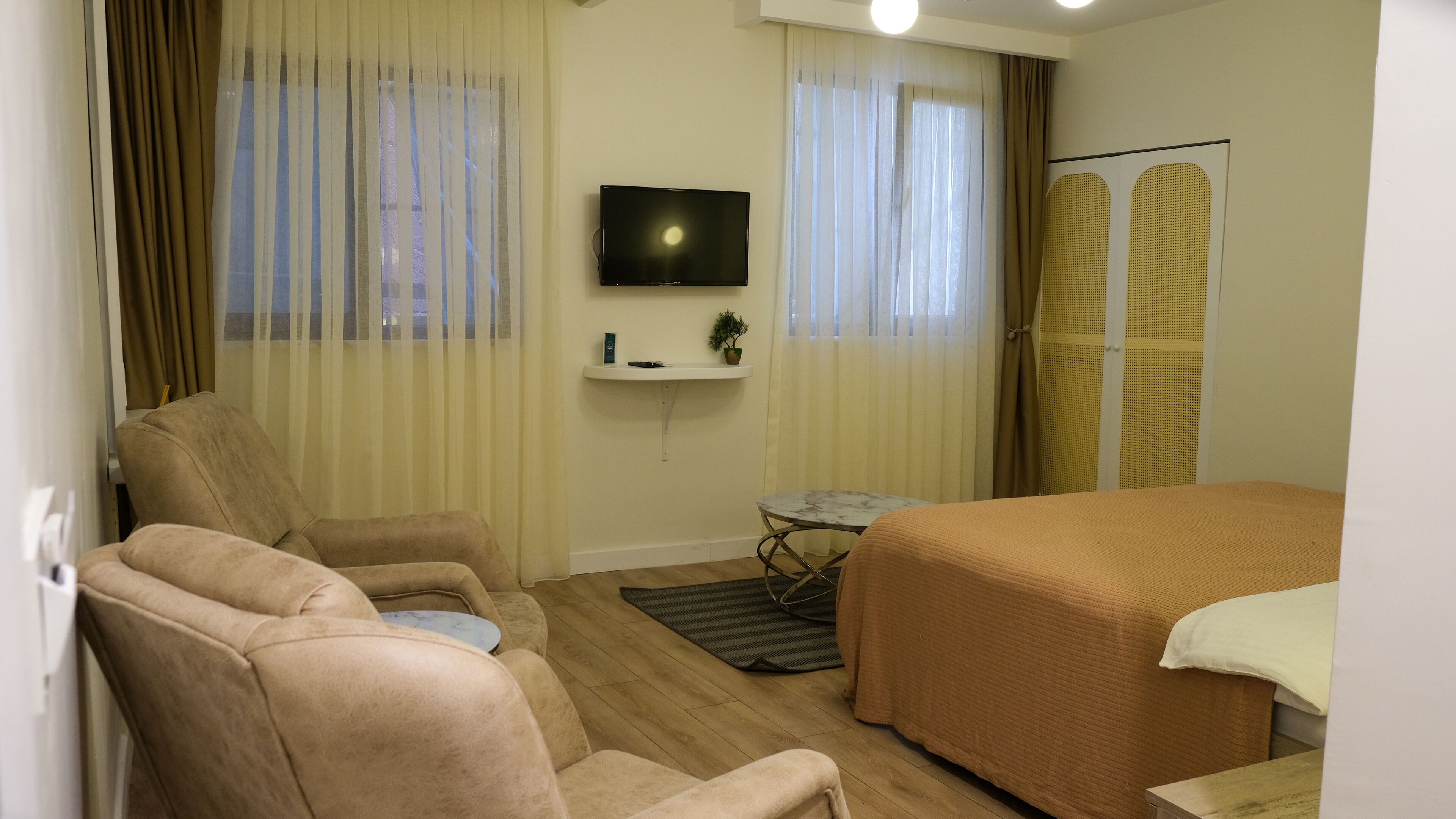 A hotel room with a bed, a sofa, a TV, and a small table.