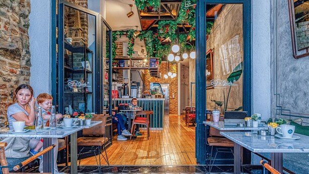 An indoor café with wooden flooring, tables, chairs, and hanging plants. - The Wilson Galata Hotel (Istanbul)