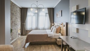 A modern bedroom with a brick wall, a large bed with a wooden headboard, a desk, and a flat-screen TV. - The Wilson Galata Hotel (Istanbul)