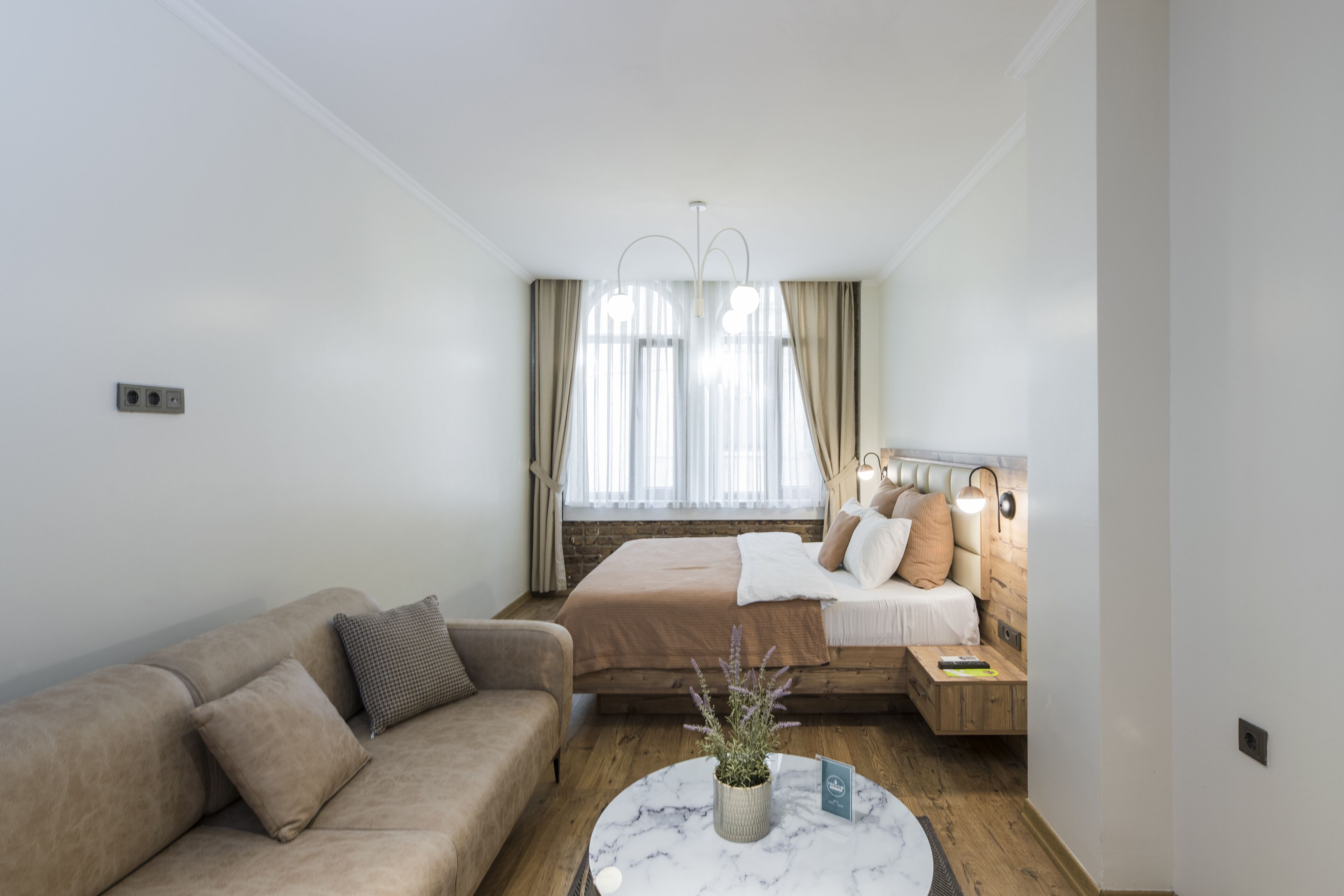 Ein modernes Schlafzimmer mit Bett, Sofa, Nachttisch und einem Marmortisch.
