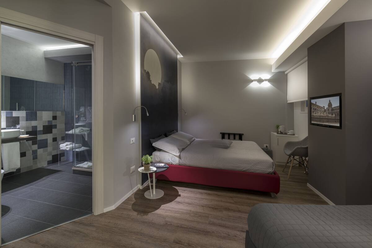 Un dormitorio moderno con cama, mesita de noche y vistas al baño.