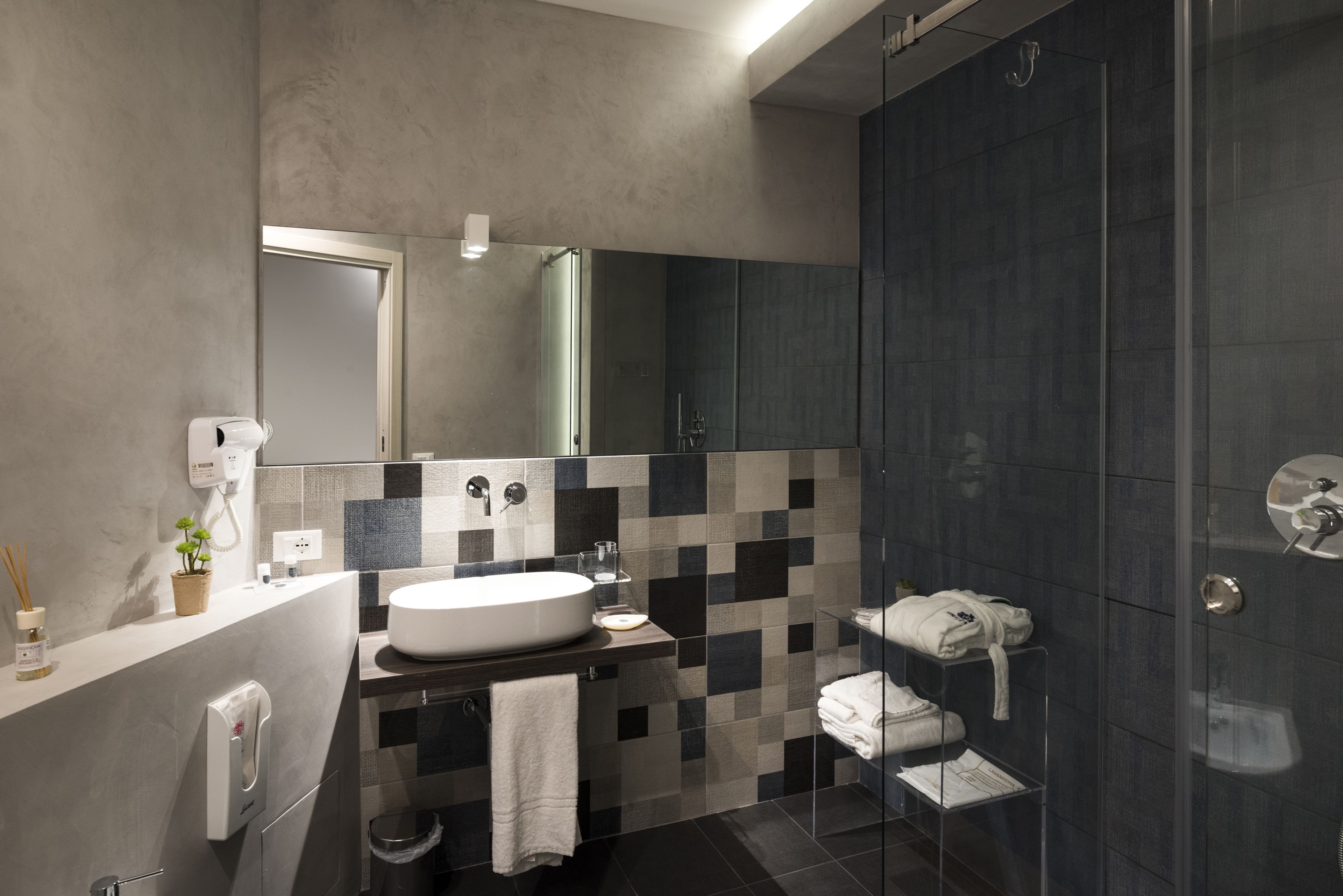 A modern bathroom with a large mirror, a sink, and a glass-enclosed shower area.