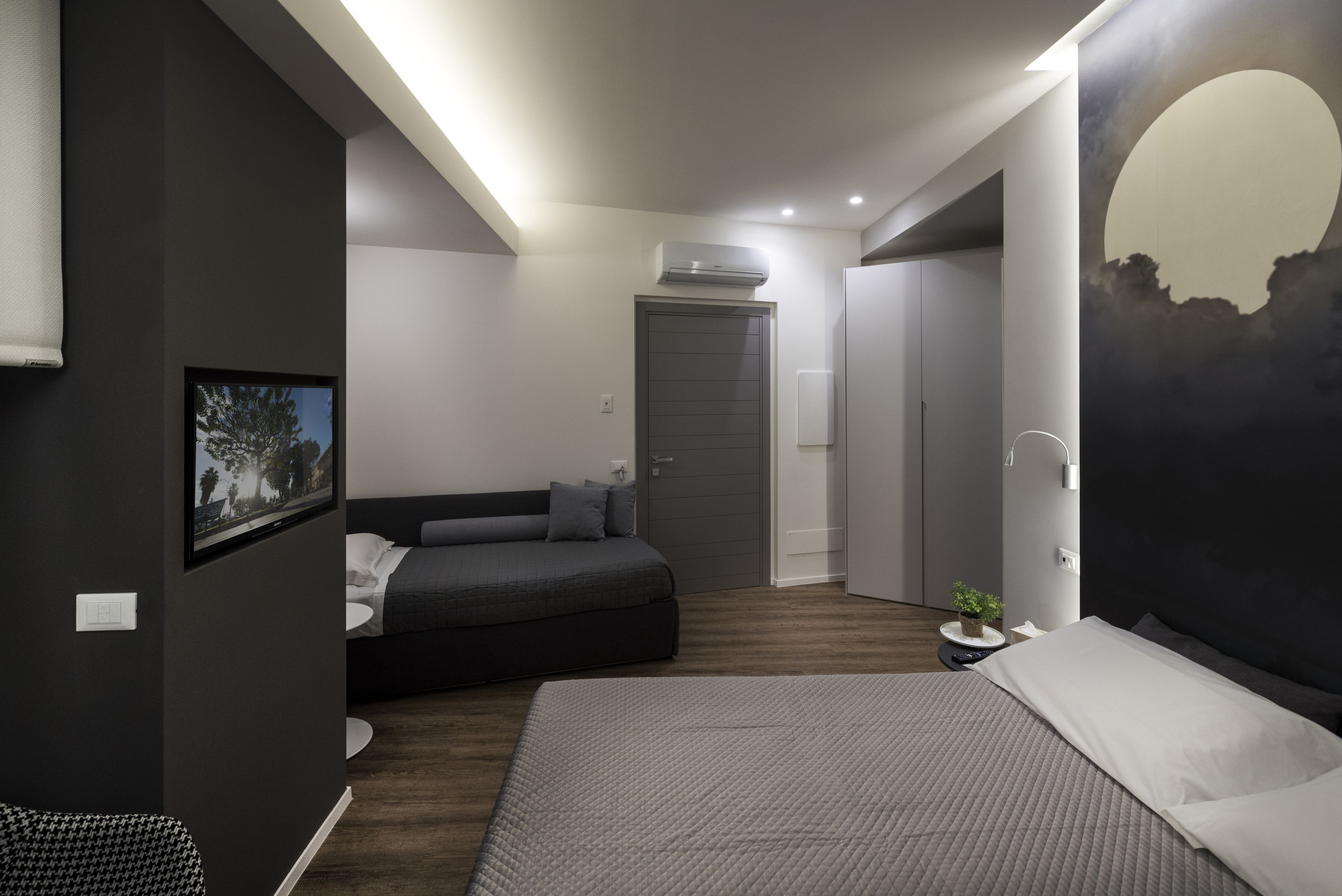 Un dormitorio moderno con una cama, un sofá y una televisión.