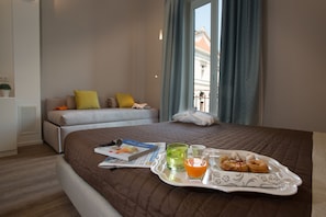 A hotel room with a bed, a bedside table with a tray of breakfast items, a window with curtains, and a view of buildings outside. - B&B In Centro Palermo (Palermo)