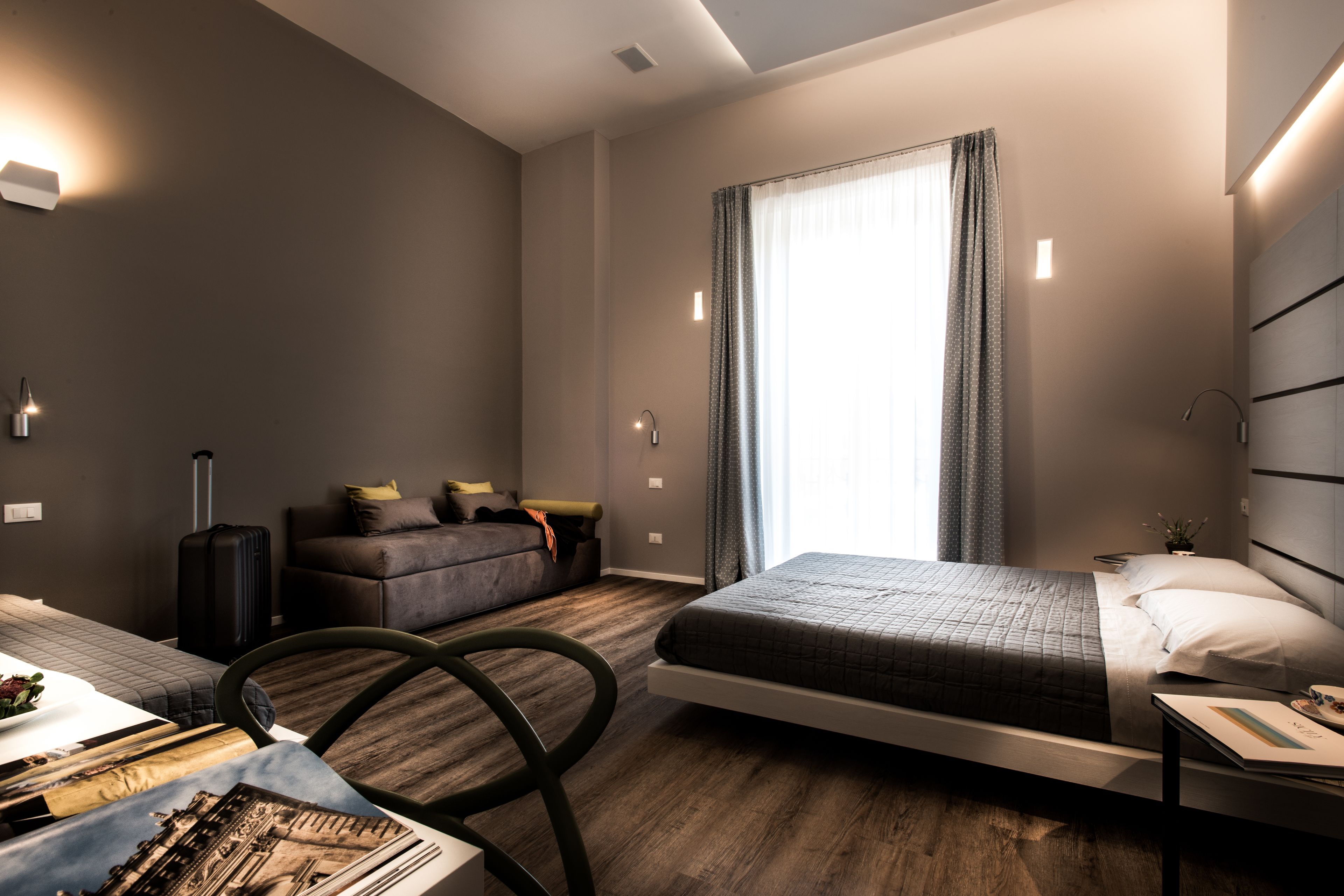 Ein modernes Hotelzimmer mit einem Bett, einer Couch, einem Schreibtisch und einem Sessel.