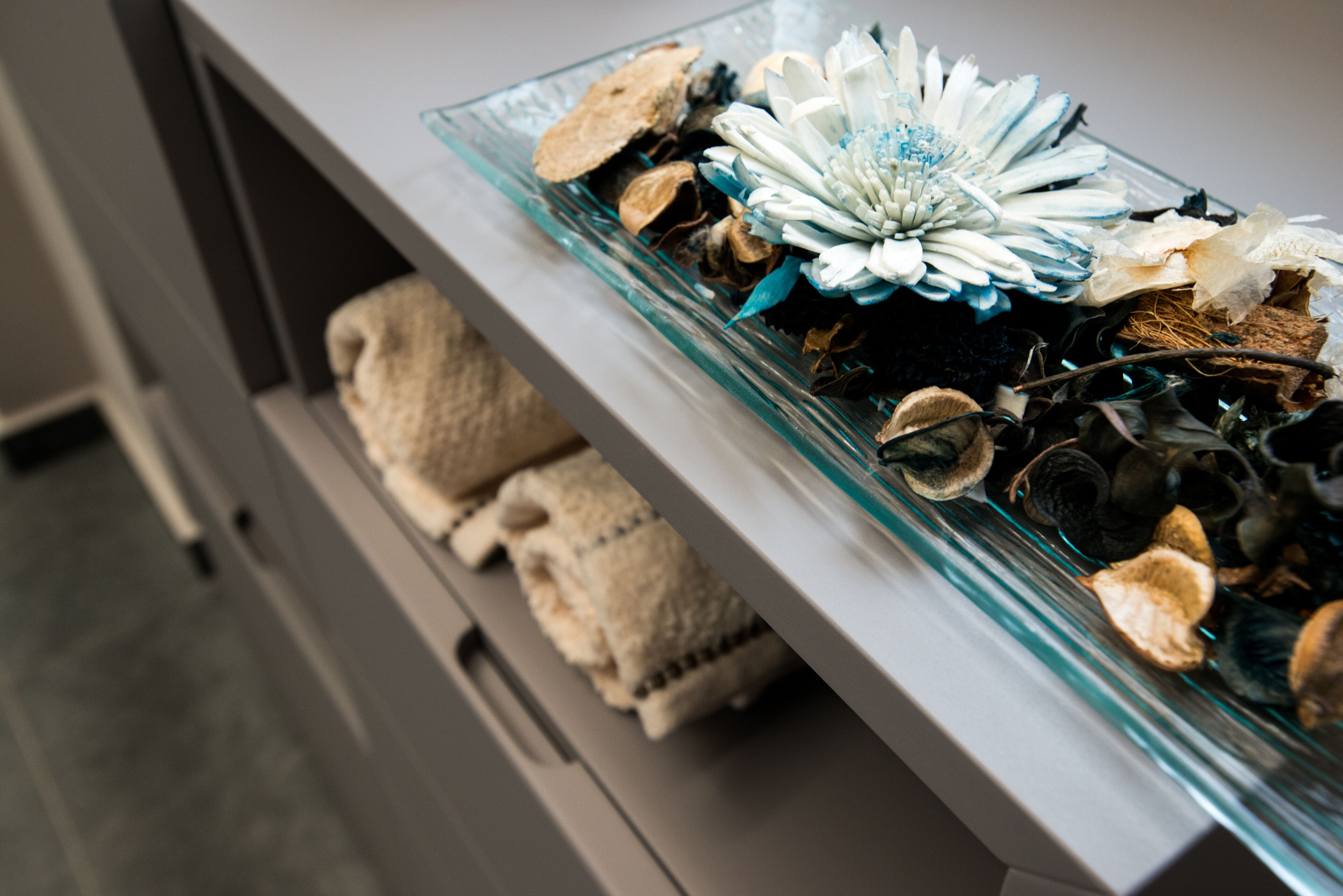 Un vitrina de vidrio con flores y hojas secas.