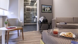 A modern hotel room with a bed, a small table with a plant, a chair, a glass of juice, and a tray with snacks. - B&B In Centro Palermo (Palermo)