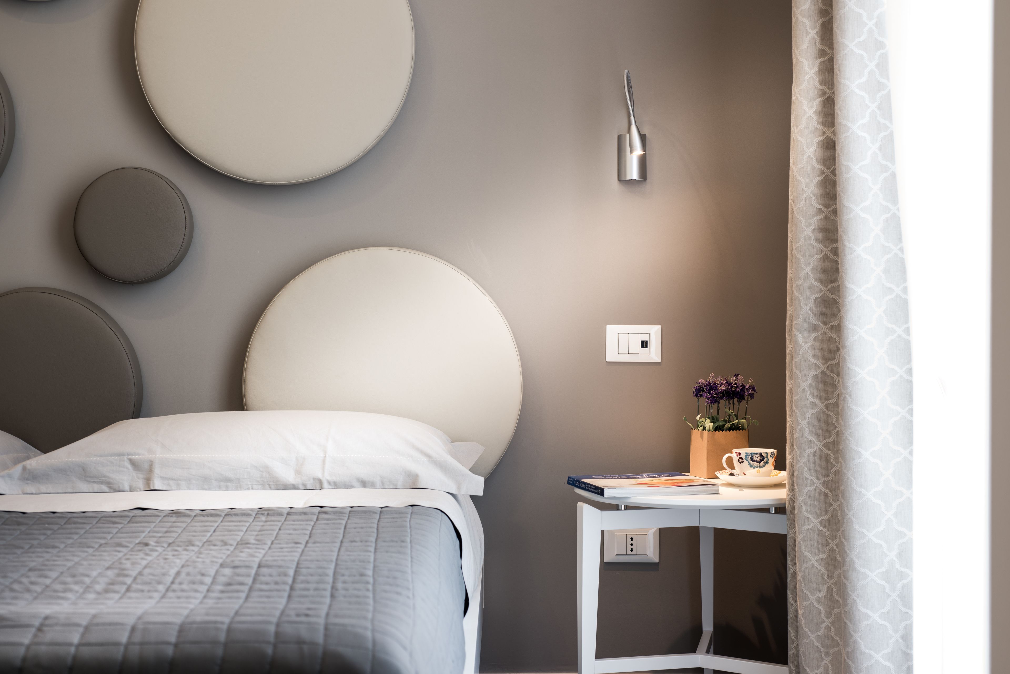 Une chambre à coucher moderne avec un lit, une table de chevet et un luminaire fixé au mur.