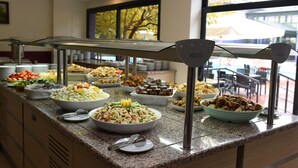 Een buffet met diverse gerechten en een uitzicht op het buitengebied door grote ramen.