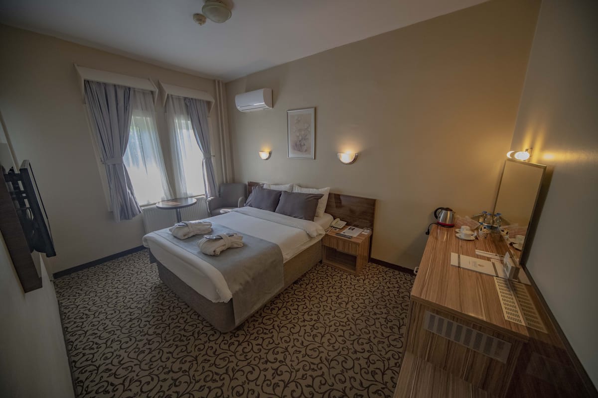 Ein Hotelzimmer mit Bett, Nachttisch, Lampe und Spiegel.