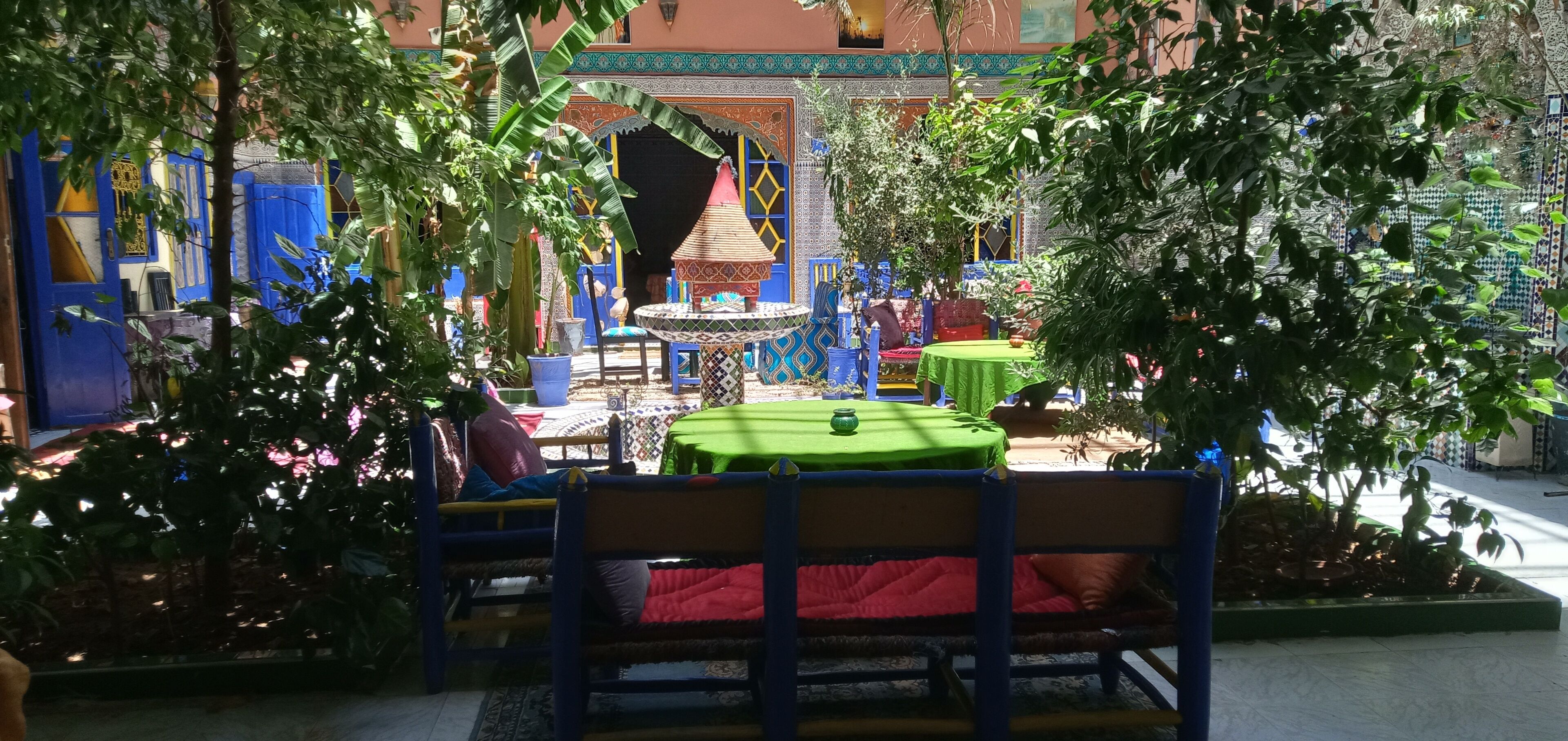 A courtyard with a central seating area, surrounded by colorful walls and potted plants.