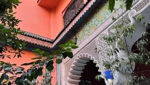 Un patio con un estilo arquitectónico tradicional, que incluye suelo de baldosas, arcos ornamentales y un balcón con barandilla.