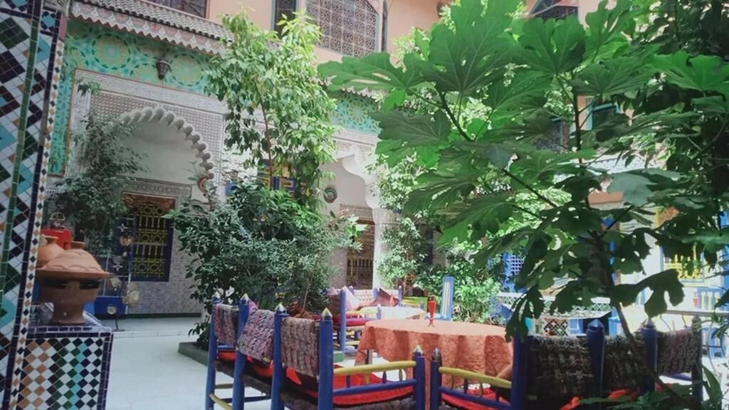 Um pátio com piso de azulejos, uma fonte e uma mesa coberta por um tecido.