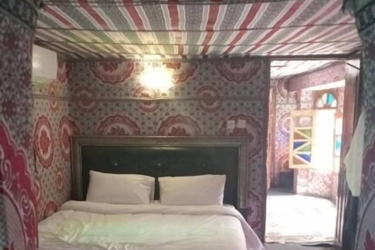 Una habitación con una cama grande, dos camas más pequeñas y un techo con diseño.