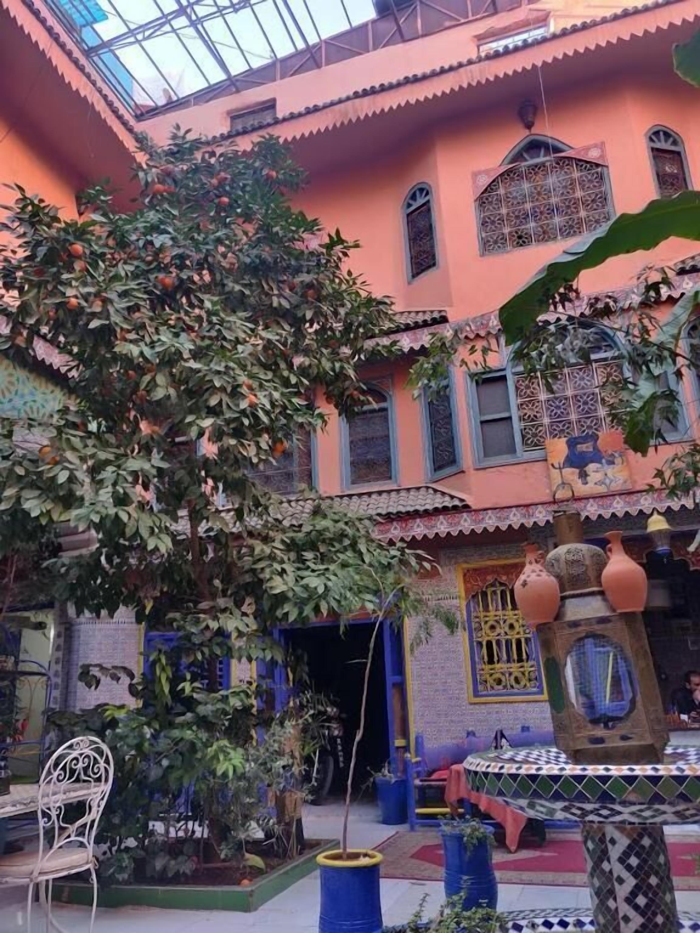 A courtyard with a tree, a fountain, and a tiled floor.